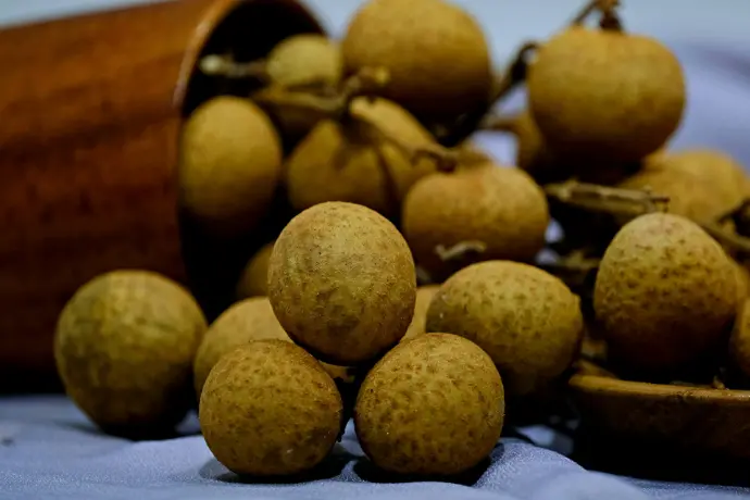 A pile of ripe longan fruits spilling from a pot.