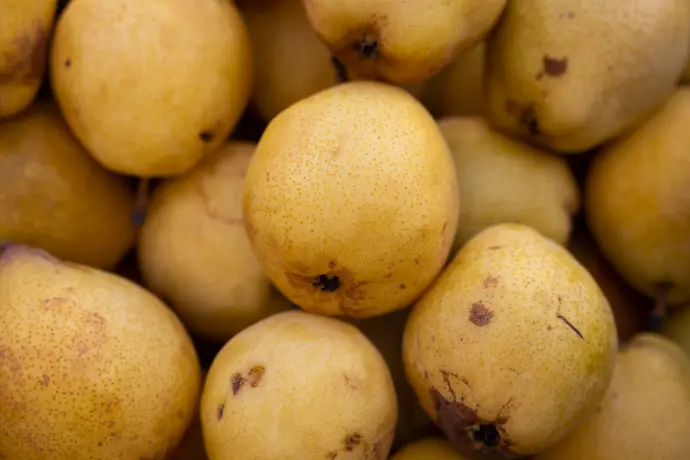 a pile of yellow pears with brown spots